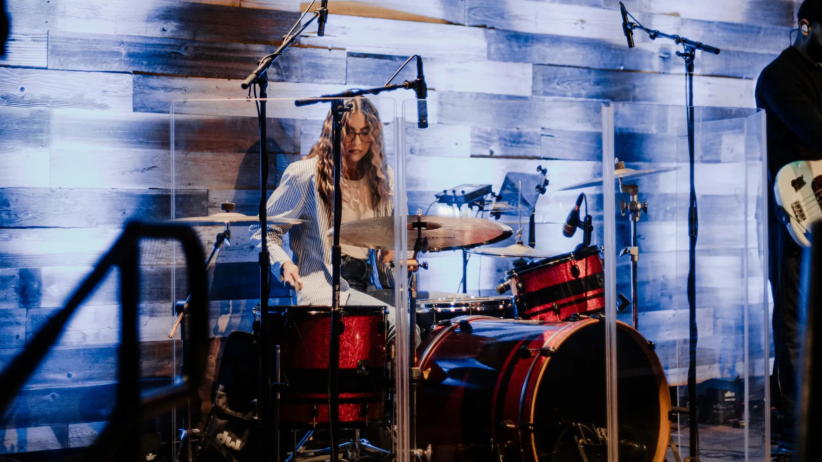 Mujer tocando los tambores rojos con fondo azul.
