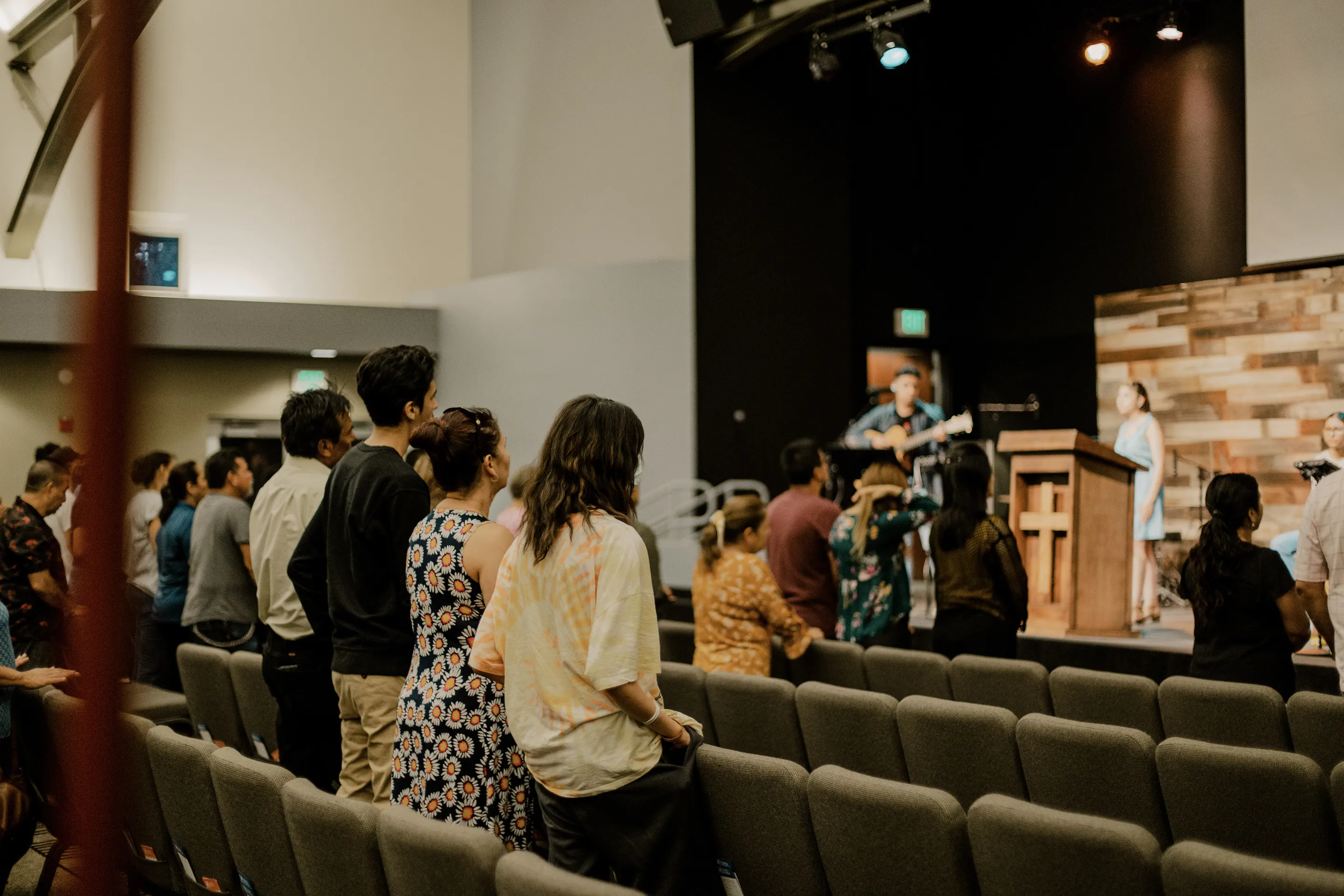 Dentro de la iglesia, la gente está de pie en adoración. La banda está jugando.