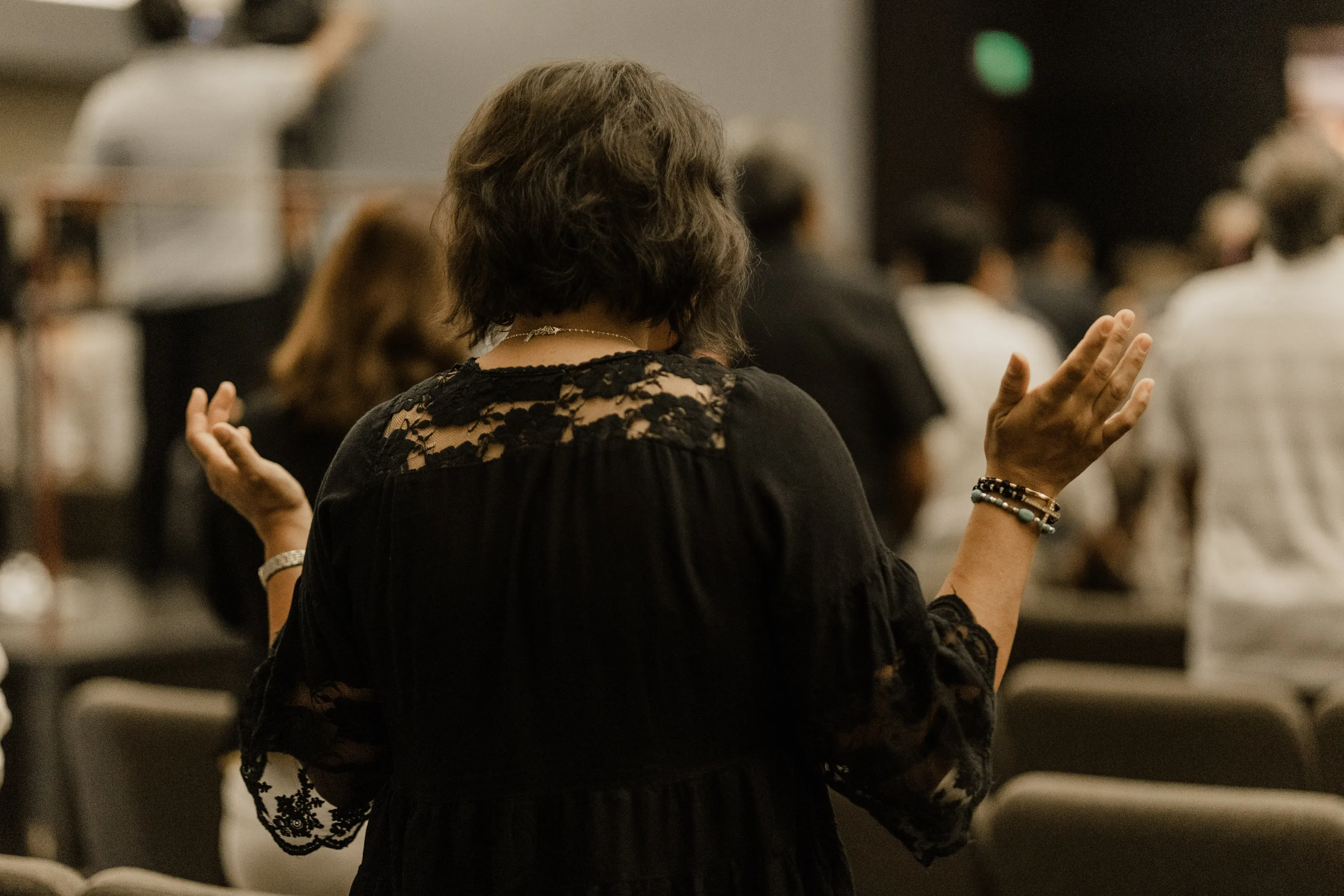 Una mujer con los brazos levantados en oración.