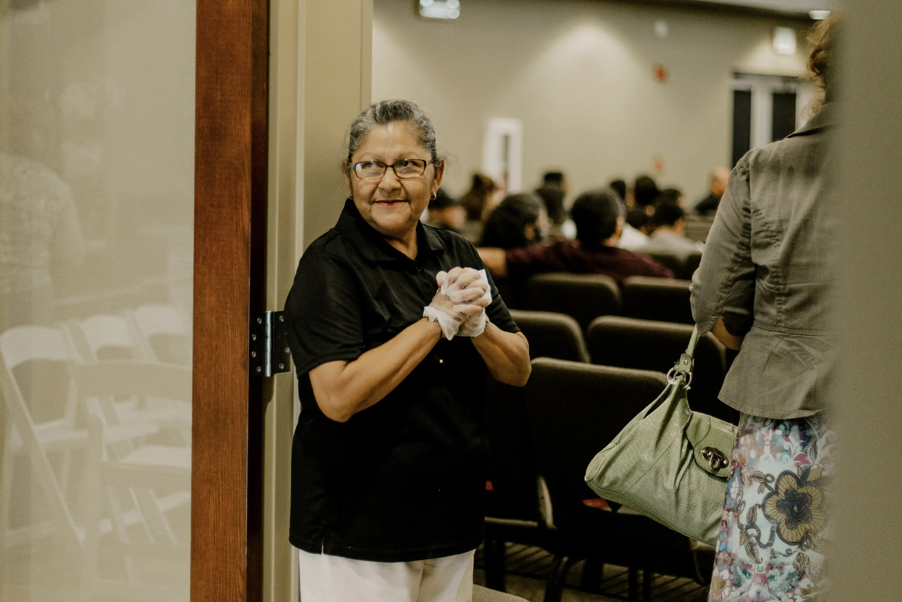 Una abuela simpatica saludando a la gente cuando entran a la iglesia.